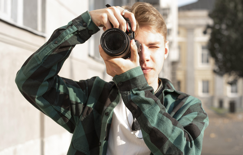 Elev som står med kamera och fotograferar.