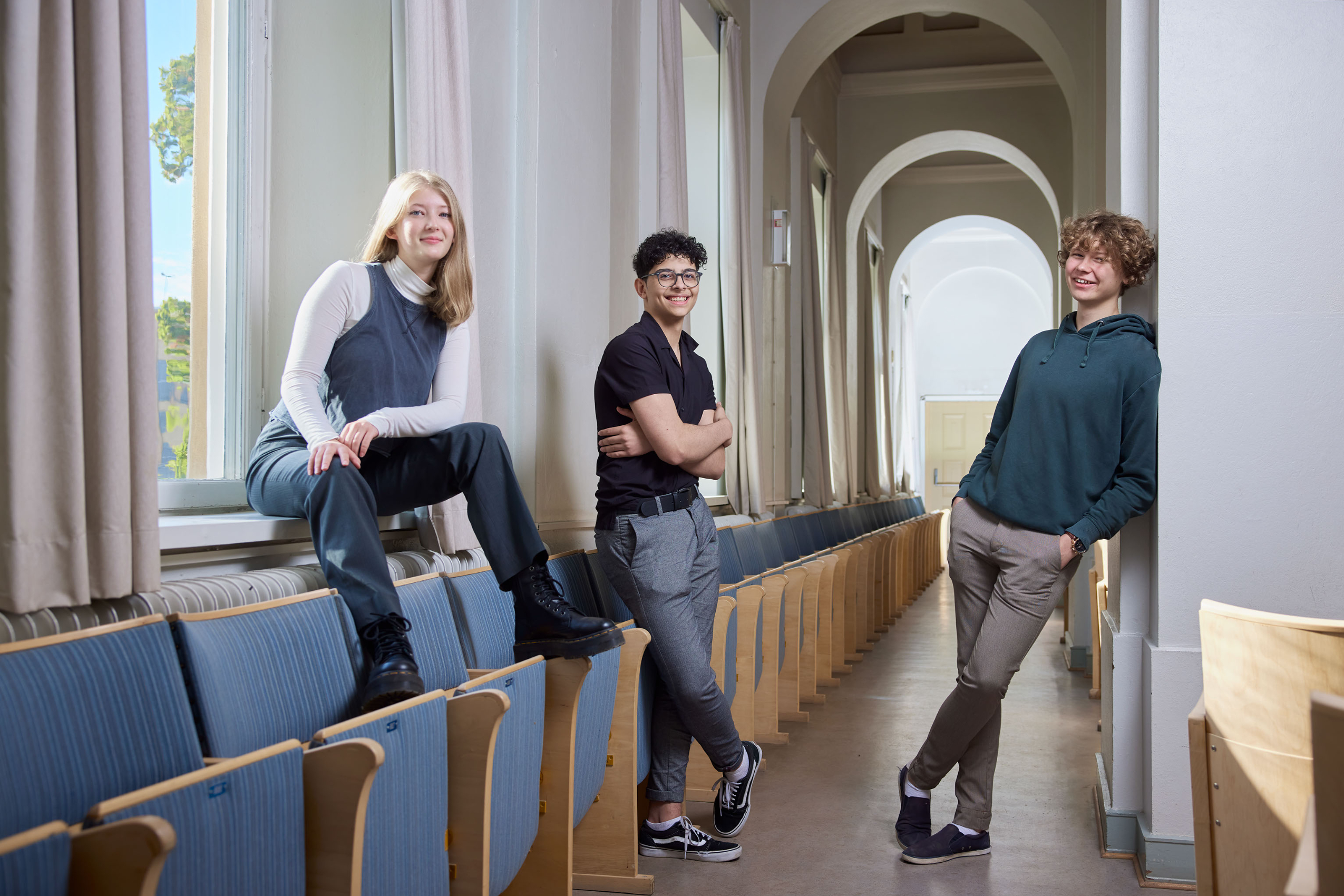 Tre elever i Brahesalen, flickan har kängor på sig, två pojkar ler glatt.