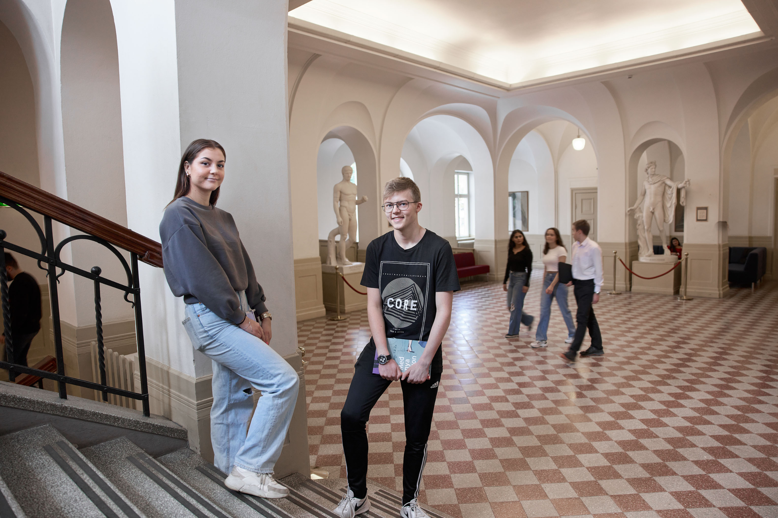 Elever på samhällsprogrammet står utanför Brahesalen, i bakgrunden syns vackra statyer och ett fint valv i taket.